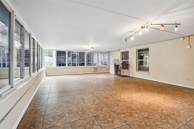 unfurnished sunroom featuring an AC wall unit, a wealth of natural light, and a notable chandelier