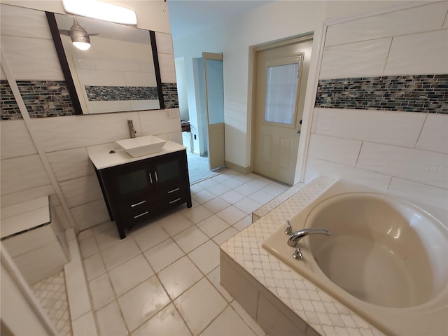 bathroom featuring tile patterned flooring, vanity, a tub to relax in, and tile walls