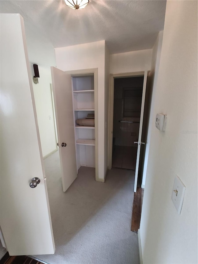 hallway with a textured ceiling and carpet floors