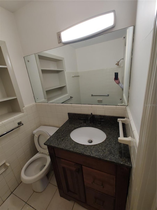 bathroom featuring tile patterned floors, vanity, toilet, and tile walls