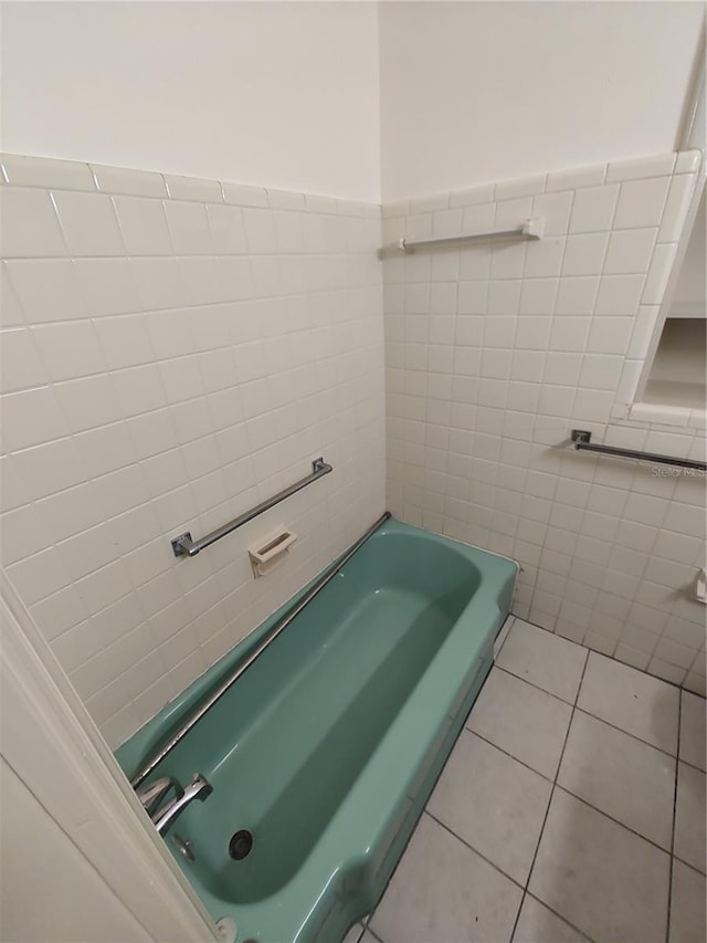 bathroom with tile patterned flooring, a tub to relax in, and tile walls