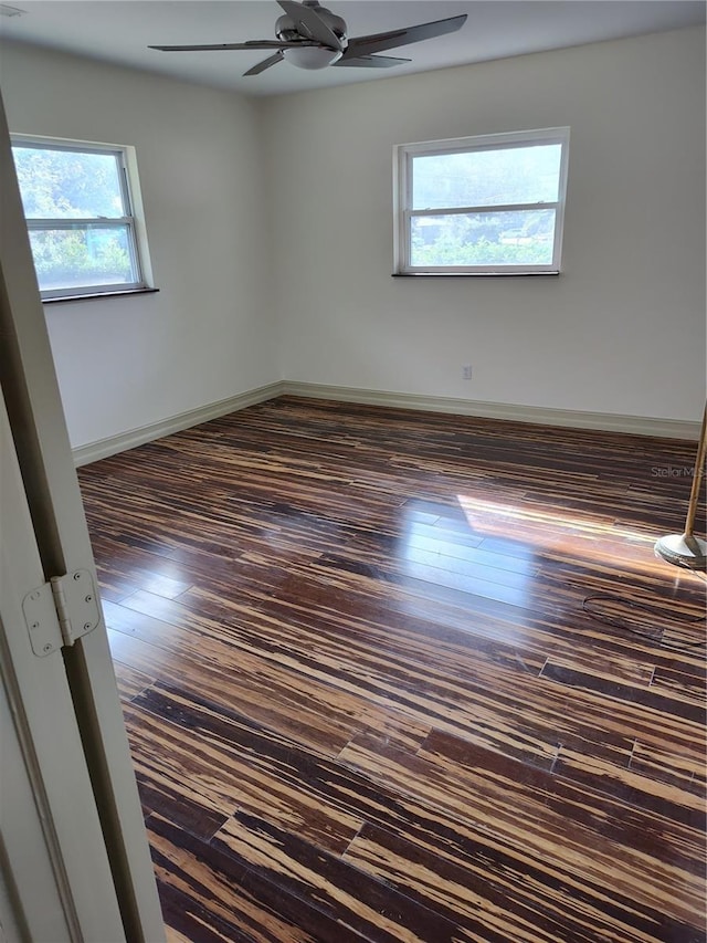 empty room with ceiling fan and dark wood-type flooring