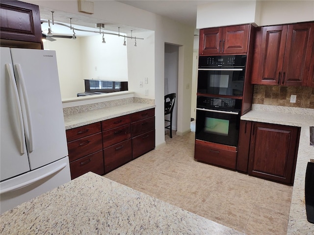 kitchen with white refrigerator, light stone counters, double oven, and backsplash