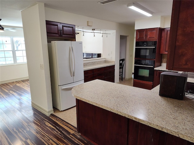 kitchen featuring white fridge, ceiling fan, and black double oven