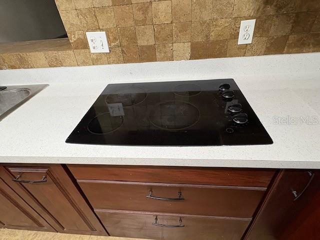 1182 Norwood Ave, Clearwater, FL 33756 - kitchen view of black electric cooktop, light countertops, and decorative backsplash