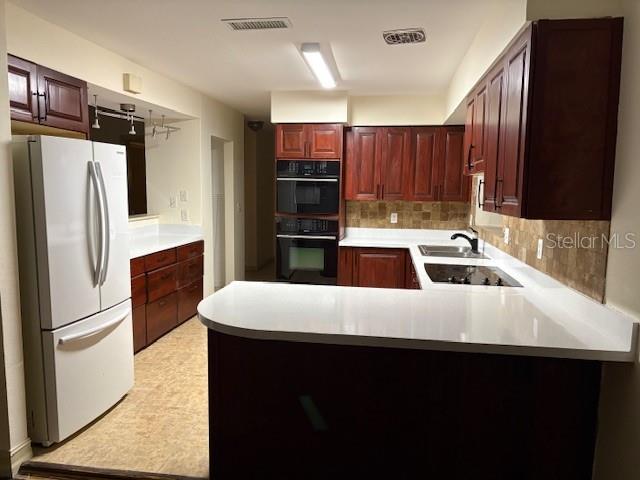 kitchen with kitchen peninsula, decorative backsplash, sink, and black appliances