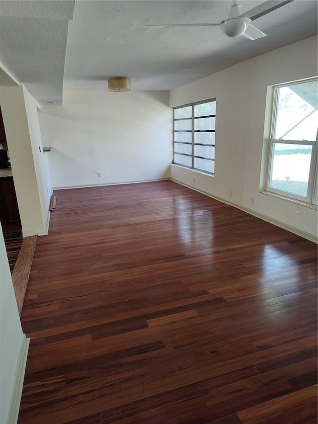 spare room featuring dark hardwood / wood-style floors, ceiling fan, and a textured ceiling