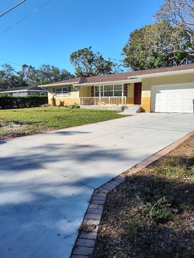 ranch-style house with covered porch, a front yard, and a garage