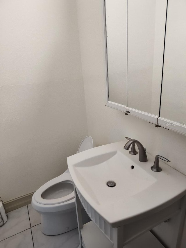 bathroom featuring tile patterned flooring, toilet, and sink