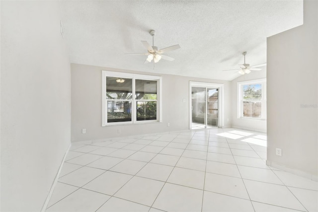 empty room featuring vaulted ceiling, ceiling fan, light tile patterned flooring, and a textured ceiling