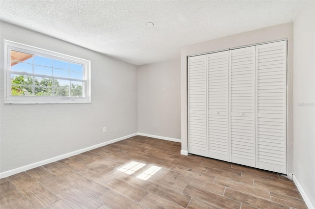 unfurnished bedroom with a textured ceiling, light hardwood / wood-style floors, and a closet