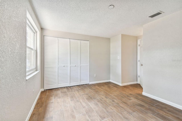 unfurnished bedroom featuring a textured ceiling, hardwood / wood-style flooring, and a closet