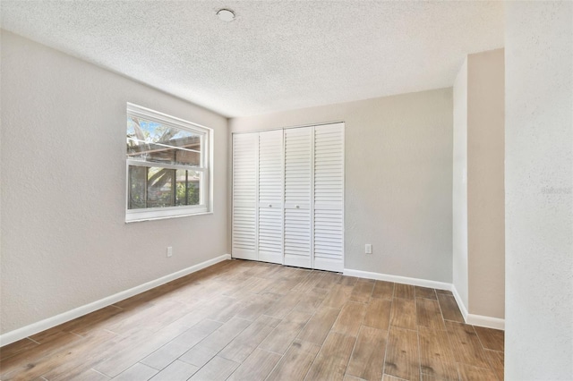 unfurnished bedroom with a closet, a textured ceiling, and light wood-type flooring