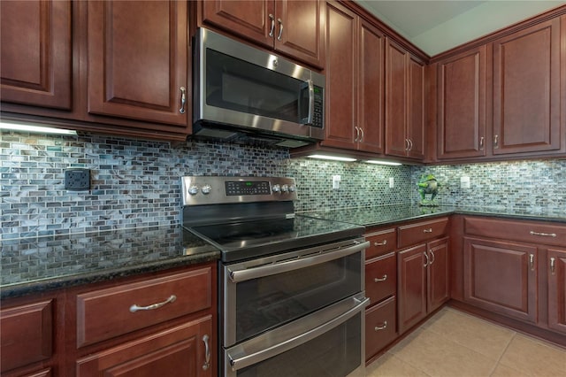 kitchen featuring decorative backsplash, light tile patterned flooring, appliances with stainless steel finishes, and dark stone counters