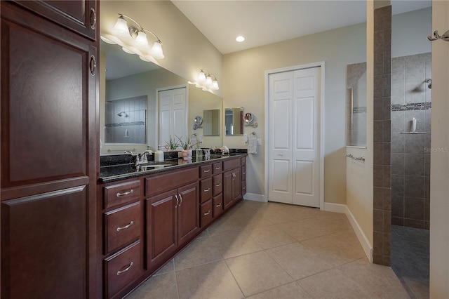 bathroom featuring tile patterned flooring, vanity, and a tile shower