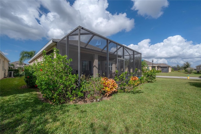 rear view of property with a lawn and glass enclosure