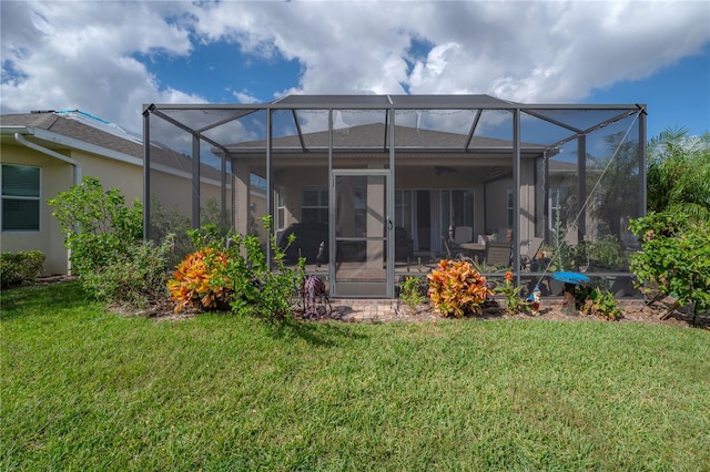 rear view of house featuring glass enclosure and a yard