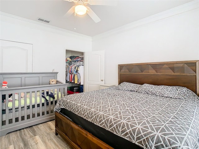 bedroom featuring crown molding, a closet, ceiling fan, and light hardwood / wood-style flooring