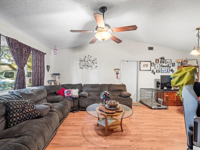 living room with a textured ceiling, ceiling fan, light hardwood / wood-style floors, and lofted ceiling