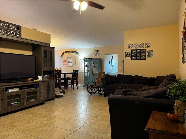 living room featuring ceiling fan, light tile patterned floors, and a textured ceiling