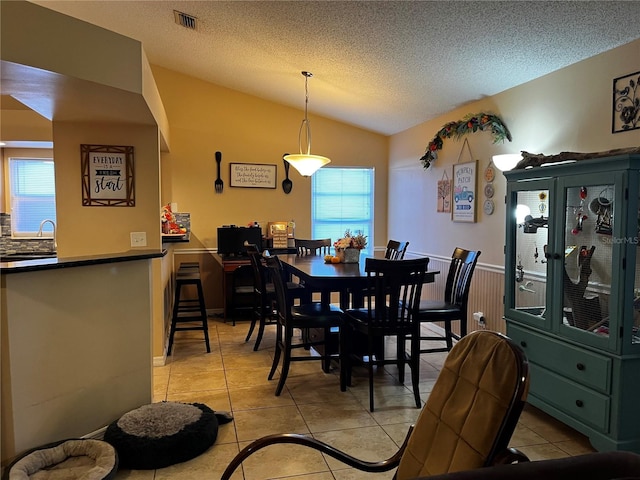 tiled dining area featuring a textured ceiling, sink, a healthy amount of sunlight, and lofted ceiling