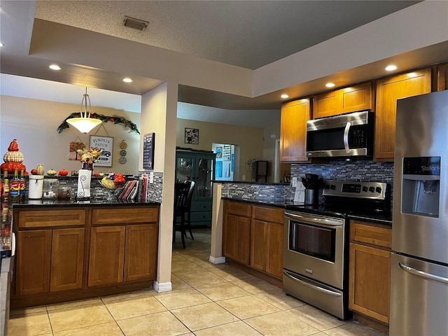 kitchen with appliances with stainless steel finishes, backsplash, a tray ceiling, light tile patterned floors, and decorative light fixtures