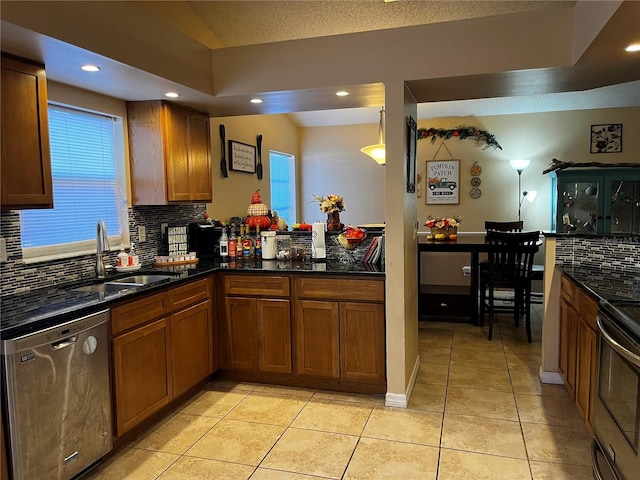 kitchen with dishwasher, dark stone counters, sink, light tile patterned flooring, and range