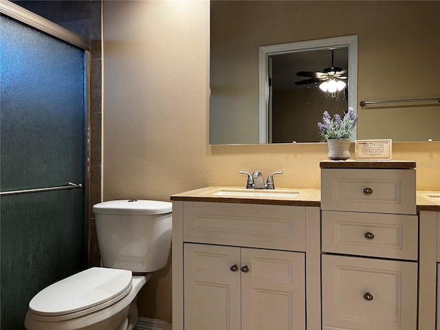 bathroom featuring vanity, toilet, ceiling fan, and a shower with shower door