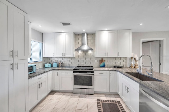 kitchen featuring white cabinetry, sink, wall chimney range hood, and appliances with stainless steel finishes