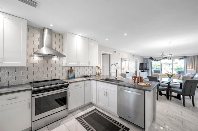 kitchen featuring white cabinets, sink, wall chimney exhaust hood, kitchen peninsula, and stainless steel appliances