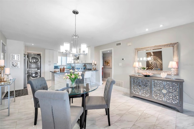 dining room featuring stacked washer / drying machine and a chandelier