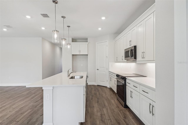 kitchen with appliances with stainless steel finishes, dark hardwood / wood-style flooring, a kitchen island with sink, sink, and white cabinets