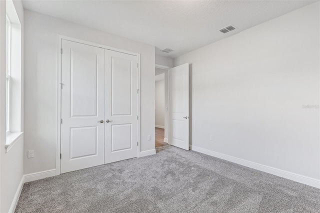 unfurnished bedroom with light carpet and a closet