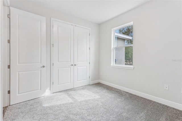 unfurnished bedroom with light colored carpet and a closet