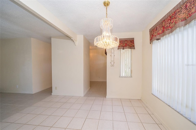 tiled empty room with a textured ceiling and an inviting chandelier