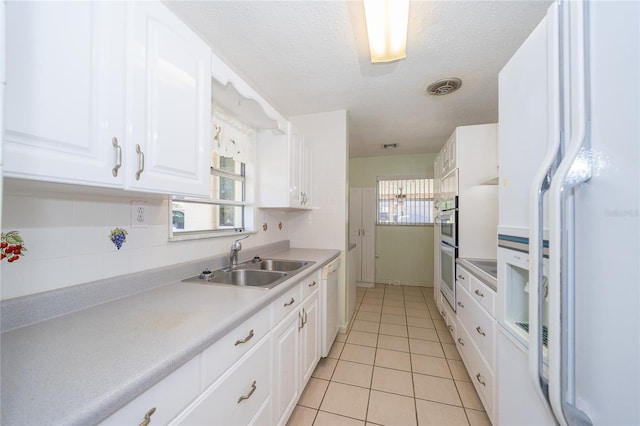 kitchen with white appliances, white cabinetry, a healthy amount of sunlight, and sink