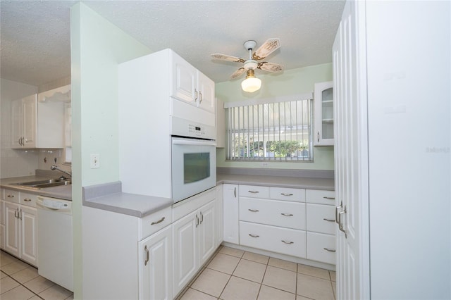 kitchen featuring white cabinetry, sink, light tile patterned flooring, and white appliances