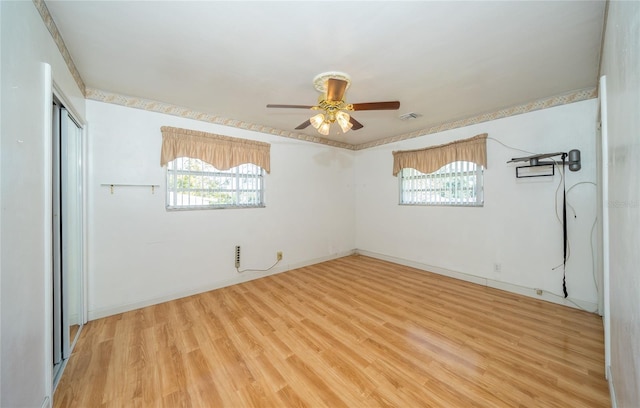 spare room featuring light wood-type flooring, a wealth of natural light, and ceiling fan