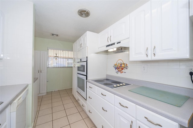 kitchen featuring tasteful backsplash, white cabinetry, light tile patterned floors, and white appliances