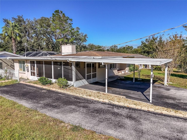 view of front of house with a sunroom, a front lawn, and a carport