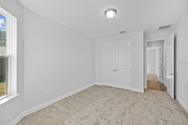 unfurnished bedroom with a closet, light colored carpet, and multiple windows