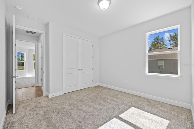 unfurnished bedroom featuring light colored carpet and a closet