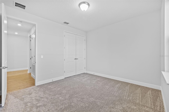 unfurnished bedroom with light carpet and a closet