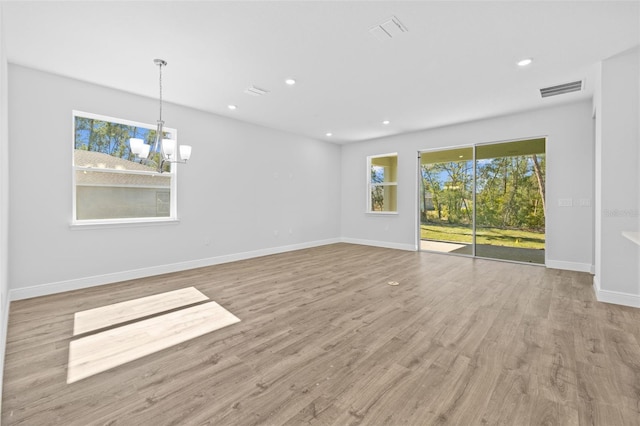 empty room with light hardwood / wood-style flooring and a notable chandelier