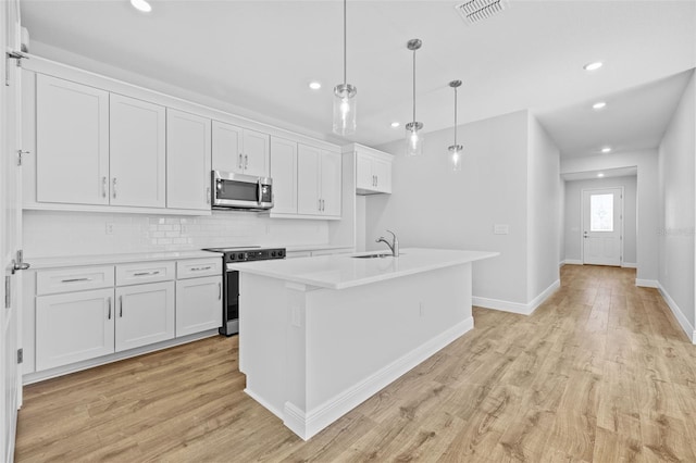 kitchen with a center island with sink, light wood-type flooring, white cabinetry, and appliances with stainless steel finishes