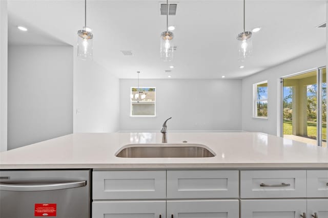 kitchen with pendant lighting, dishwasher, light stone countertops, and sink