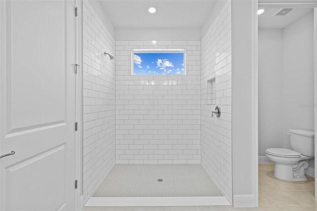 bathroom featuring tile patterned flooring, tiled shower, and toilet