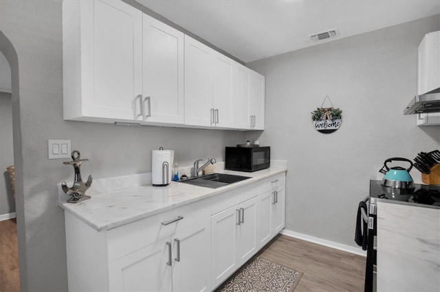 kitchen featuring white cabinetry, sink, stainless steel range, and light stone counters