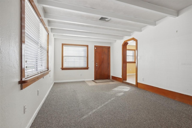 empty room with beamed ceiling and carpet flooring