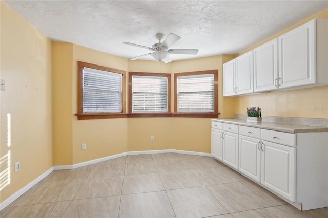 kitchen featuring white cabinetry, light tile patterned floors, ceiling fan, and a textured ceiling